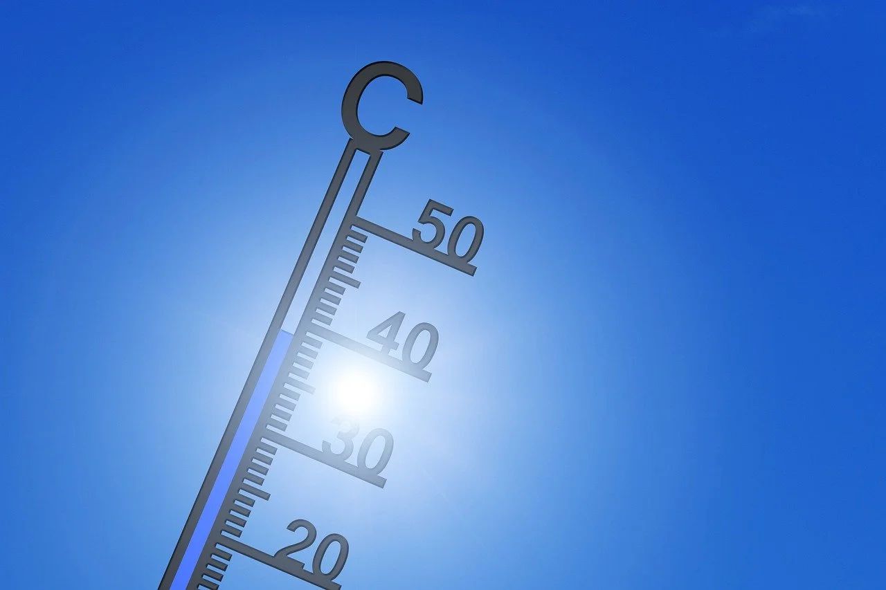 Un thermomètre indique plus de 40 °C devant un soleil éclatant, dans un ciel bleu sans nuage.