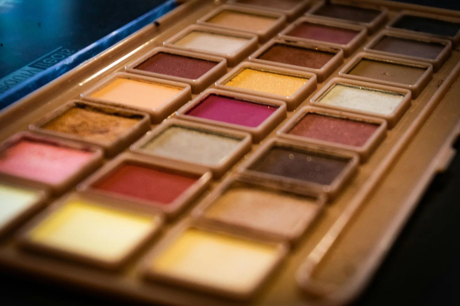 Une palette de fards à paupières aux tons roses, dorés et bruns, vue de près.