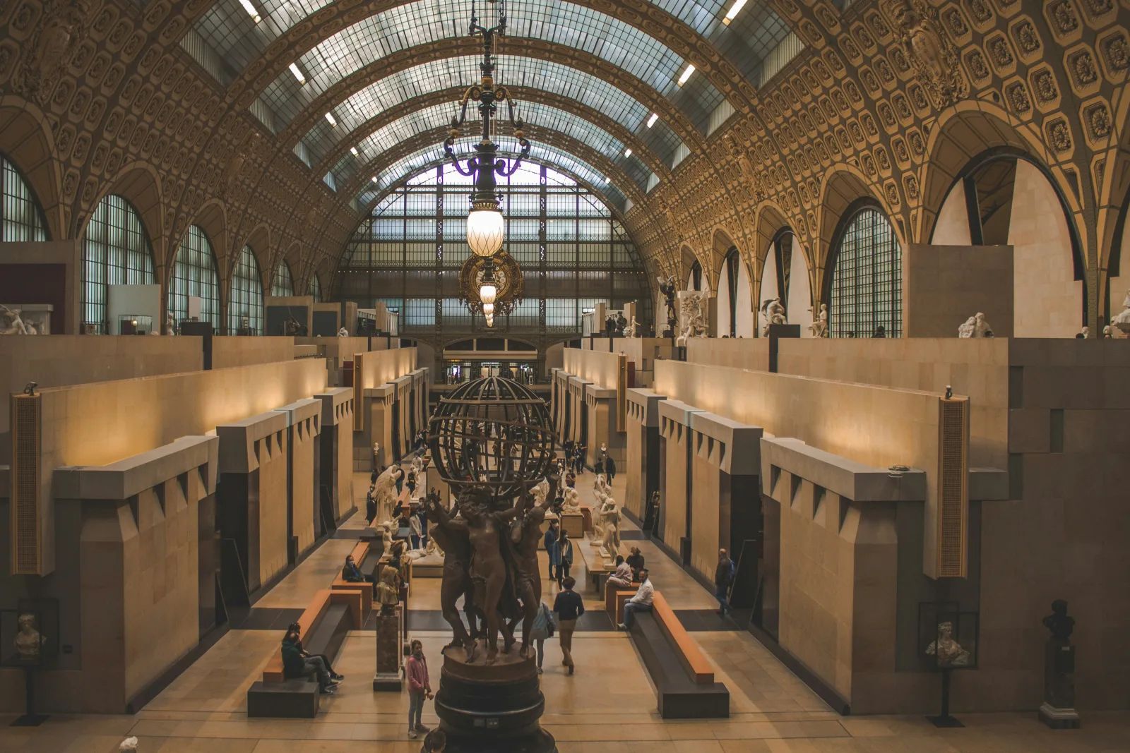 La grande nef du musée d’Orsay vue d’en haut, sous sa verrière, avec ses sculptures et ses visiteurs.