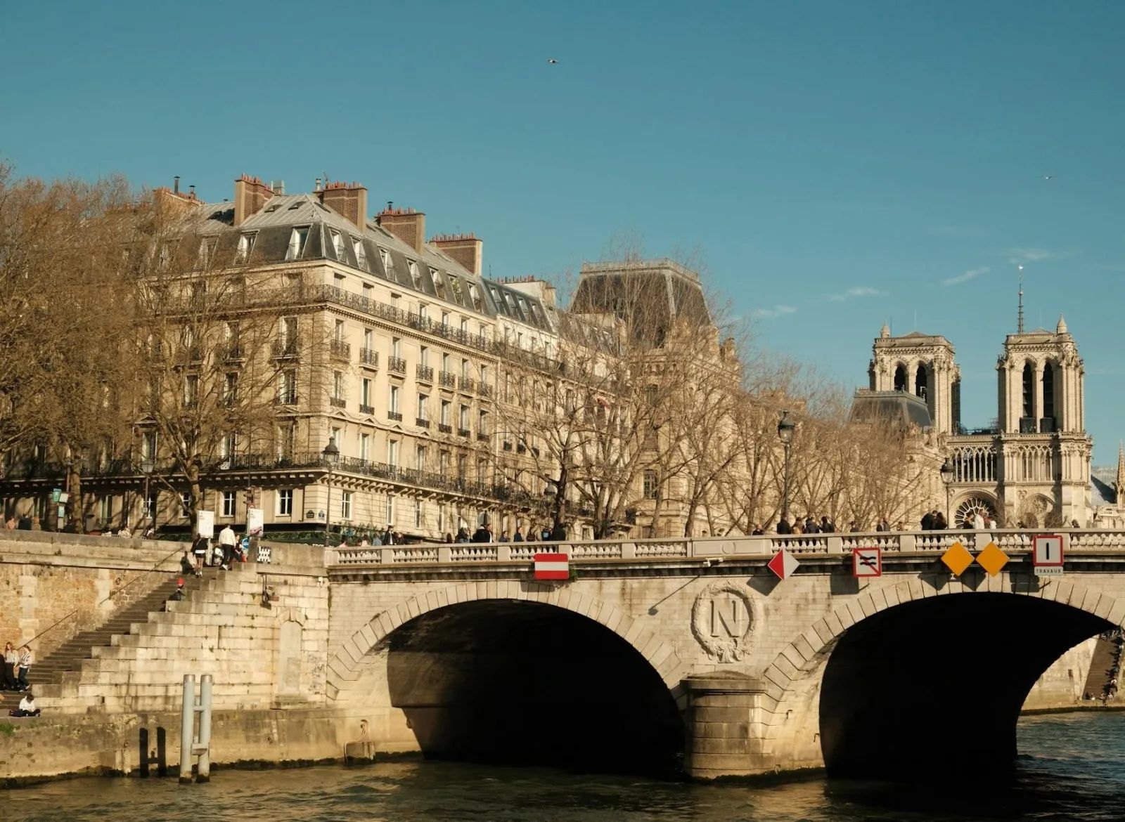 Un pont de pierre sur la Seine, à Paris, avec les tours de la cathédrale Notre-Dame à l’arrière-plan.